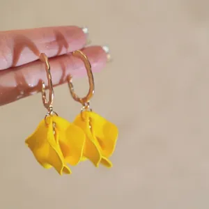 Close-up detail of yellow flower petal hoop earrings with gold geometric fashion design