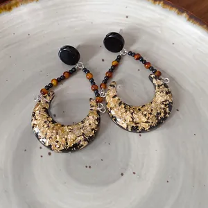 Détail de la texture de feuilles d'or dans la résine noire de boucles d'oreilles lune