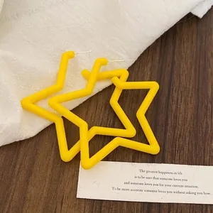 Detail of bright yellow star-shaped earrings with a matte texture on aesthetic props.