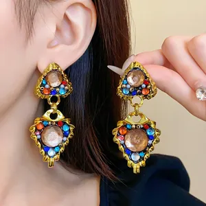 Close-up of vintage royal style gold-tone earrings with colorful rhinestones on model