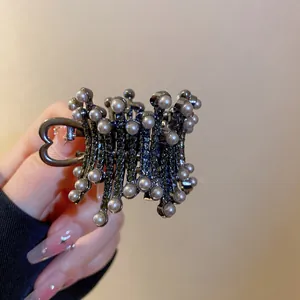 Macro detail of a elegant black crown hair claw clip decorated with white pearls