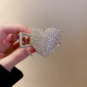 Close-up detail of a sparkling rhinestone heart-shaped hair claw clip in gold finish