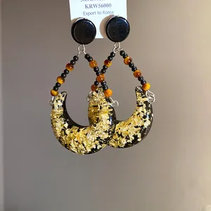 Gros plan de boucles d'oreilles lune en résine avec feuille d'or et perles