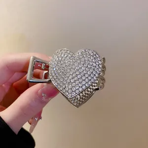 Detail view of a sparkling silver heart-shaped hair claw clip with pavé rhinestones