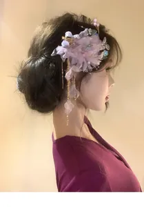 Elegant purple fabric mesh flower hair clip with hanging gold tassels on a model