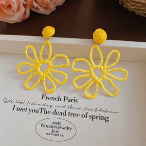 Detailed view of handmade yellow woven flower earrings on a decorative display box