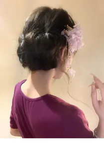 Detailed view of sweet fabric mesh flower hair clip with golden tassels on bun hairstyle