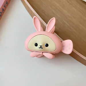 Detail view of a cute pink matte rabbit-shaped hair claw clip with a decorative bow-tie.