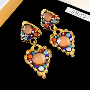 Macro view of vintage gold-tone drop earrings with vibrant multicolored rhinestones