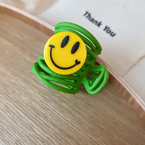 Detailed macro view of a vibrant green hair claw clip with a classic yellow smiley face decoration