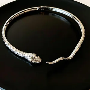 Elegant silver-toned snake choker necklace featuring green gem eyes on a black surface