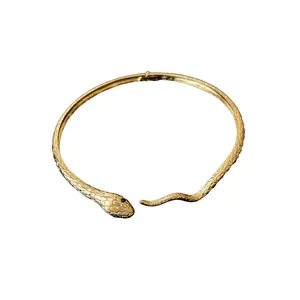 Minimalist gold-plated snake shaped choker necklace featuring green crystal eyes