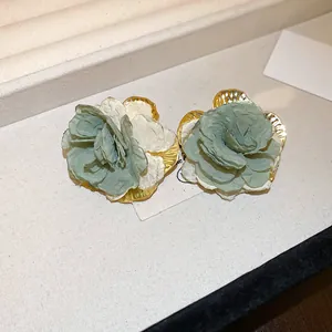 Detailed macro shot of elegant sage green and white spray-painted resin flower stud earrings