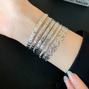 Elegant set of silver-toned stacked bracelets with intricate floral and star textures on wrist