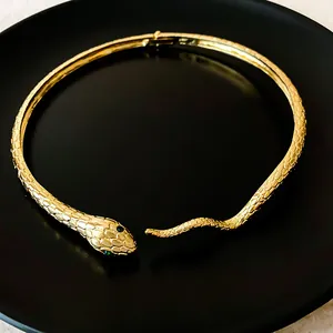 Close-up of golden snake choker featuring intricate scale texture and green eyes