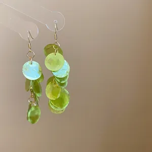 Macro detail of lime green resin round disc drop earrings with silver needle hooks