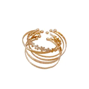 Set of gold-toned cuff bracelets with floral and textured patterns for a stylish look.