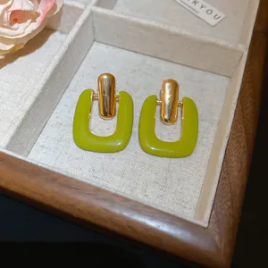 Close-up detail of lime green resin U-shaped earrings displayed in a wooden jewelry box