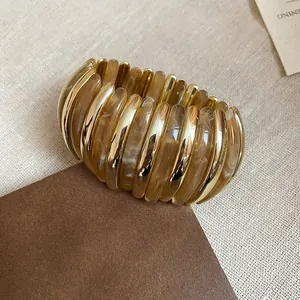 Fashionable elastic cuff bracelet with amber marble texture and gold metallic finish.