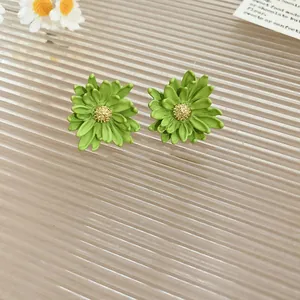 Detailed view of matte green resin flower stud earrings with gold center on glass