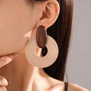Detail shot of bohemian wooden spiral hoop earrings with vintage ethnic design on model.
