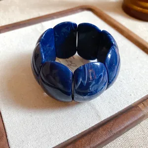 Detail view of a chunky blue marbled acrylic bracelet with a smooth polished finish.