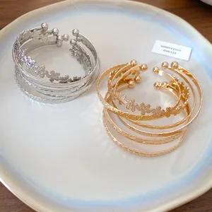 Detailed view of silver and gold open cuff bracelets with flower and star patterns.