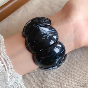 Detailed macro view of a black marble pattern acrylic chunky bracelet worn on a wrist