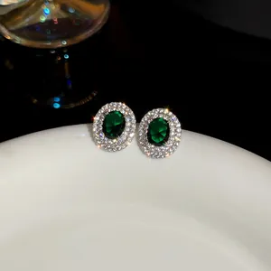 Macro view of vintage oval emerald-green resin stud earrings with double crystal halo