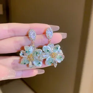 Close-up of floral resin earrings with iridescent petals and sparkling crystal accents