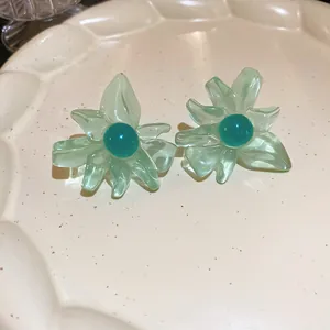 Close-up of mint green resin flower earrings with teal center on a ceramic plate