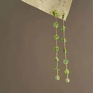 Macro view of forest style long dangle earrings featuring green translucent resin beads