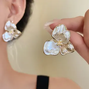 Close-up of elegant French vintage three-petal flower earrings with a pearlescent finish