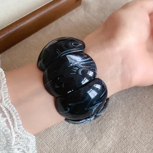 Close-up detail of a chunky black and white marbled acrylic bracelet on a wrist