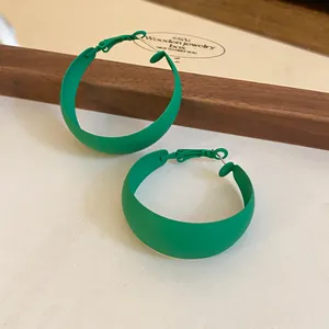 Close-up view of green matte spray-painted hoop earrings in a forest style design