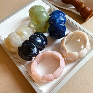 Macro detail of colorful acrylic marbled bracelets arranged on a white display tray.