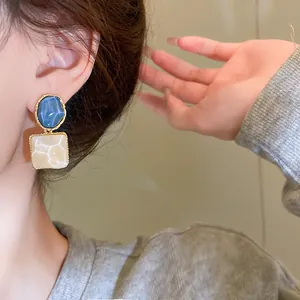 Elegantes pendientes cuadrados irregulares con patrón de mármol azul y blanco en modelo