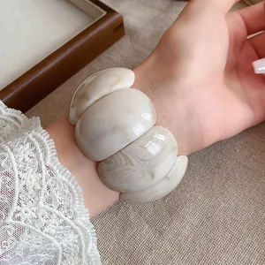 Close-up of marbled acrylic chunky bracelet worn on wrist with lace sleeve detail