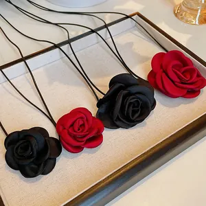 Detailed view of handmade red and black fabric rose necklaces on a minimalist display tray