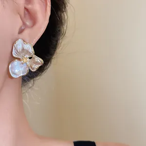 Close-up detail of vintage white three-petal flower stud earrings with gold plating