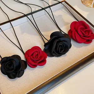 Close-up detail of handmade fabric rose flower necklaces with thin leather cords in a tray