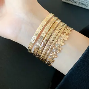 Elegant stacked gold-plated bangles set featuring delicate star, moon, and flower patterns.