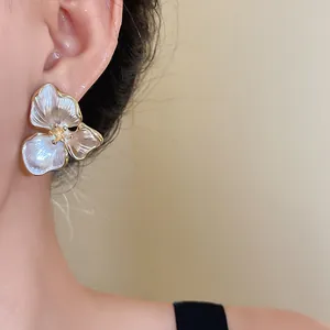 Close-up detail of French vintage three-petal flower earrings with iridescent finish