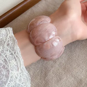 Detail view of a chunky pink marbled acrylic bracelet with elegant swirled patterns