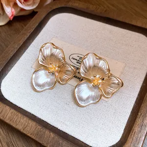 Detailed view of French vintage three-petal flower stud earrings with pearlescent finish