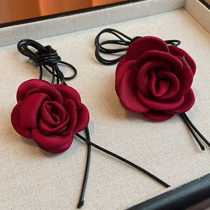 Detailed view of dark red fabric rose necklaces with black braided cords on display tray.