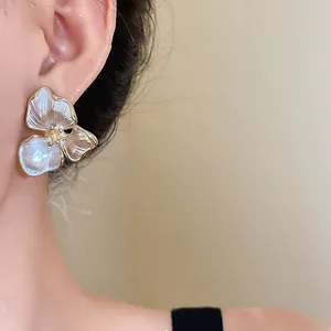 Detailed view of elegant vintage white three-petal flower stud earrings with gold edges