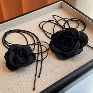 Macro detail of elegant black fabric rose choker necklace with thin woven cord pendant
