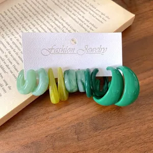 Set di orecchini a cerchio in acrilico verde e giallo su cartoncino portagioielli