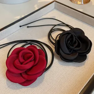 Detailed view of handmade fabric rose necklaces in red and black with thin black cords
